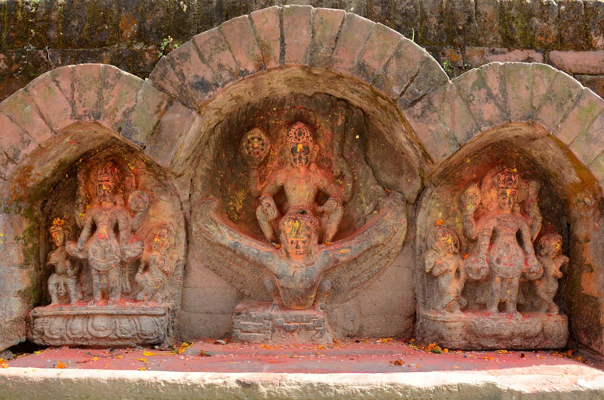 Kathmandu Changu Narayan 34 Three Images Of Vishnu, One Riding Garuda, On West Side Of Parijat Tree Platform On North East Side Of Changu Narayan Three statues of Vishnu are on the west side of the parijat tree platform in the north east area of Changu Narayan. The middle Vishnu holds a chakra wheel and a long mace club in his raised hands and is shown riding Garuda. Each of the left and right Vishnus hold a chakra wheel and a mace club, standing between two smaller figures.
